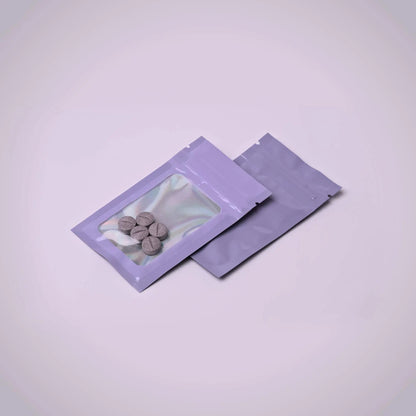 Two purple transparent packaging pouches with small 7ohBLACK 7-oh items inside on a light purple background