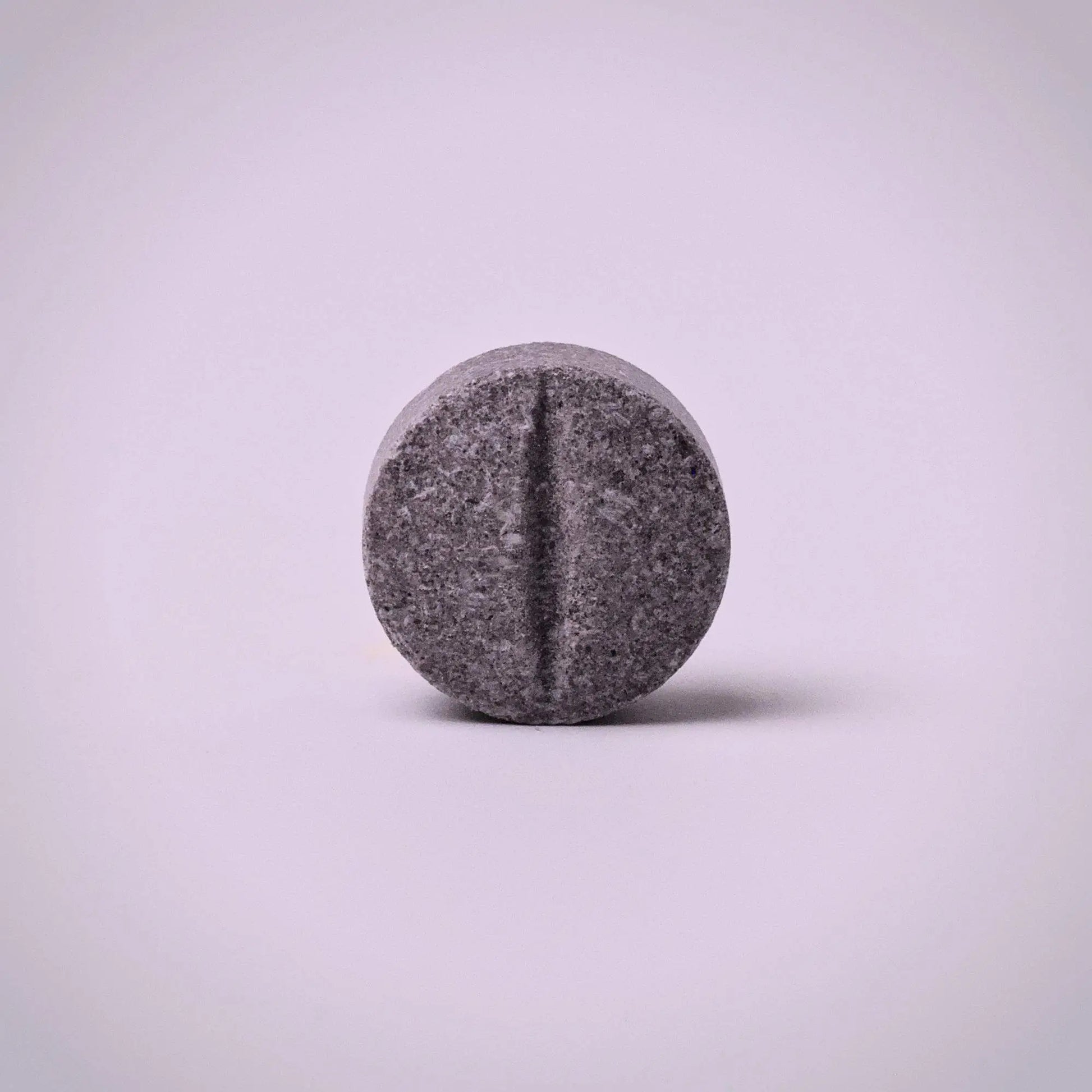 Gray 7ohBLACK 7-oh pill-like object on a light purple background